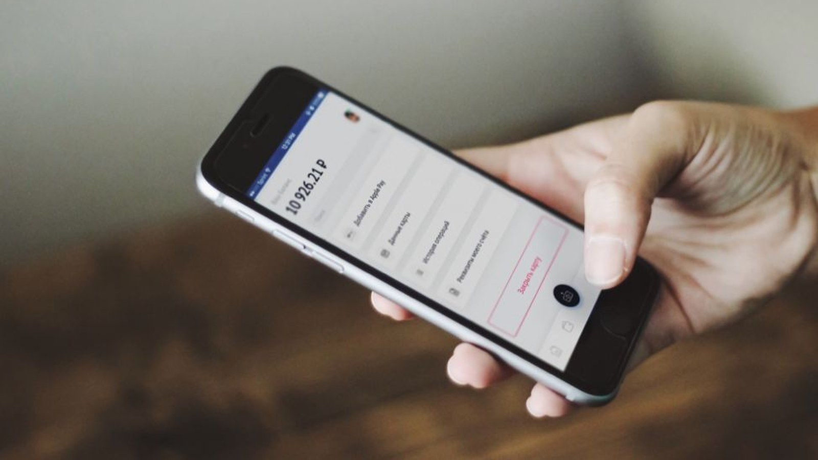 Hand holding a smartphone with messages near an office desk